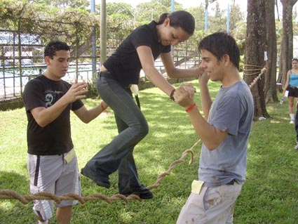 Joven cruza sobre una cuerda asistida por compañeros