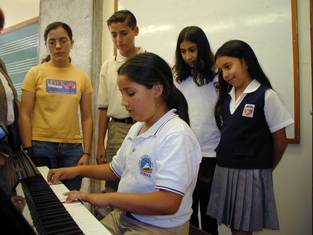 Niña tocando piano y niños observando