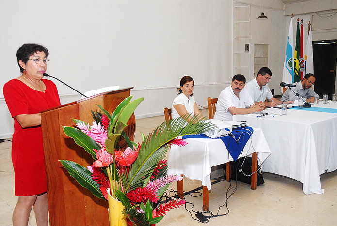 Flor Garita hablando en podio y mesa principal atrás