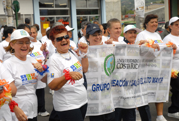 Adultas mayores sosteniendo pancarta y riendo en caminata