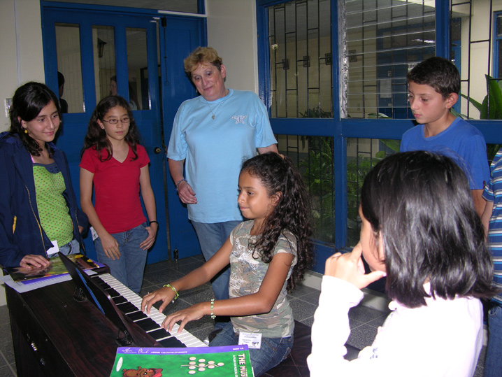 Niña en piano y compañeros observando