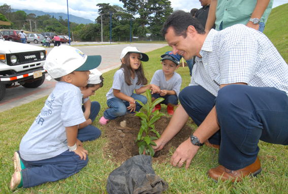 Adulto y niños sembrando árbol
