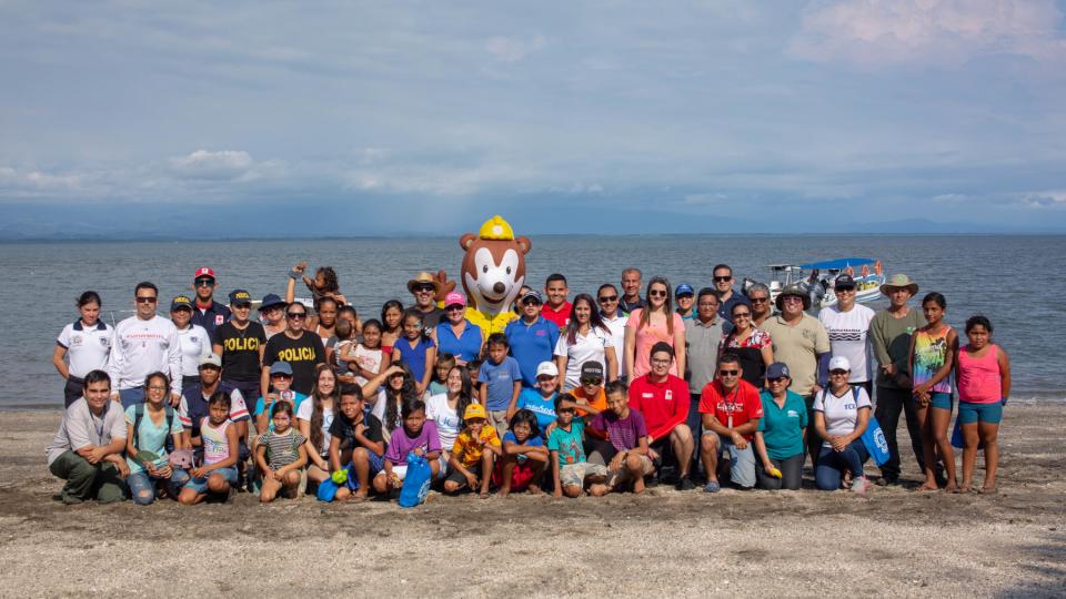 Grupo de personas participantes posan para la foto frente al mar