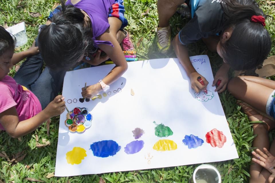 Un grupo de niñas indígenas pinta con acuarelas sobre una cartulina