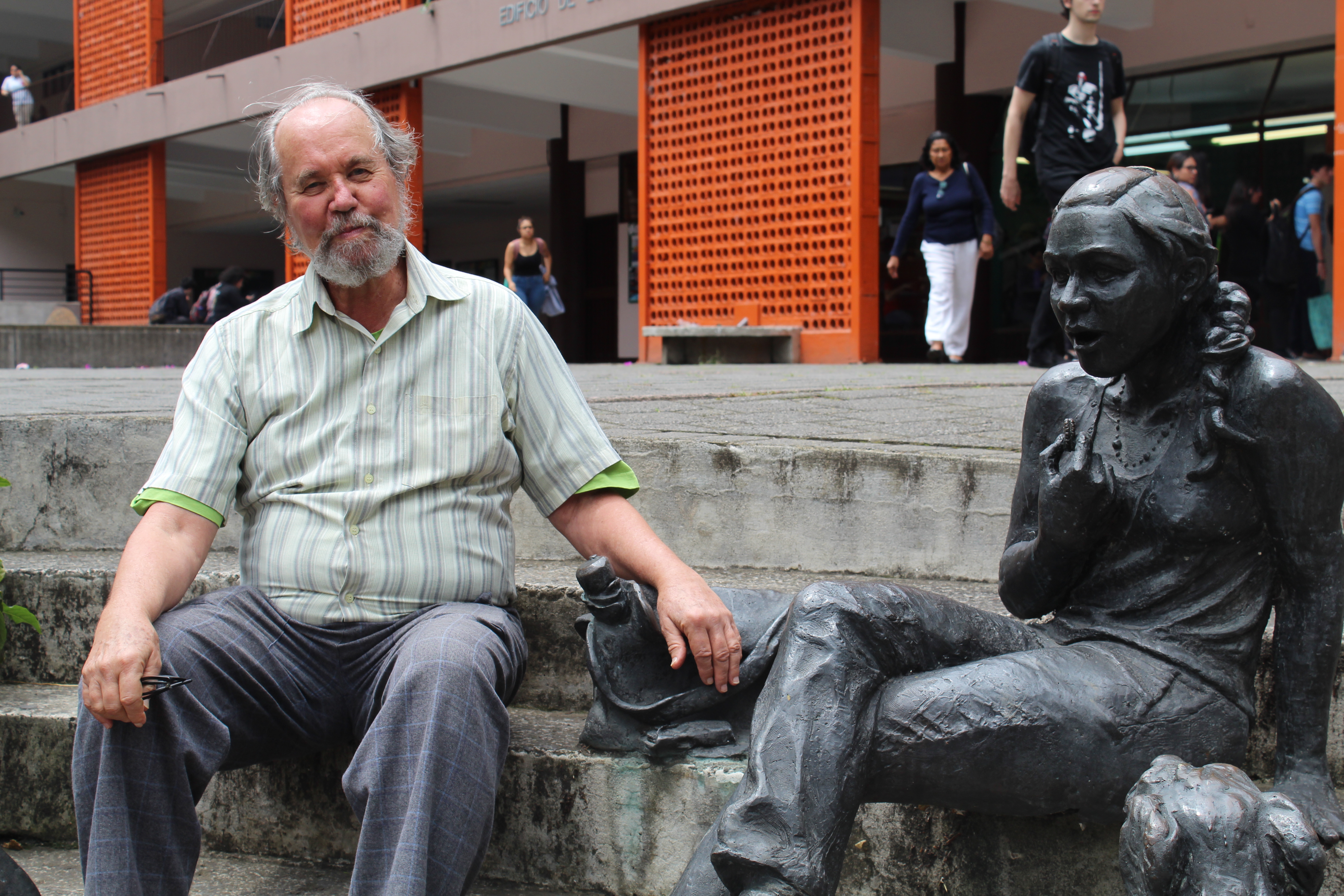 Antropólogo Carlos Rodrigues sentado junto a una estatua en el pretil