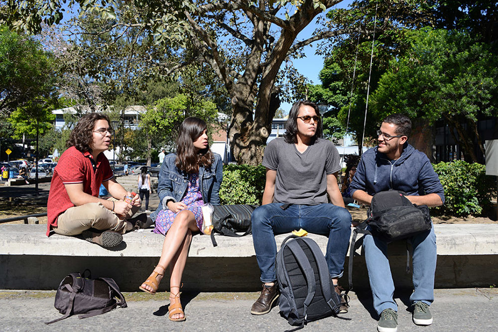 4 estudiantes conversan frente a la biblioteca Carlos Monge Alfaro