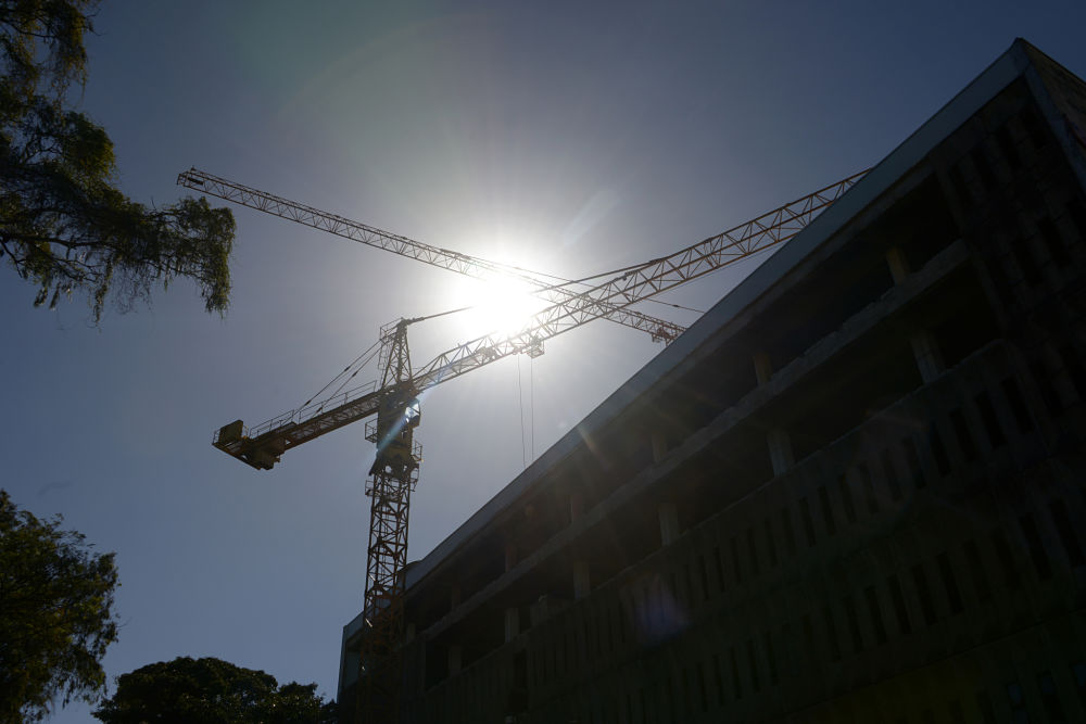 Dos grúas de construcción entrecruzadas sobre un edificio en obra gris