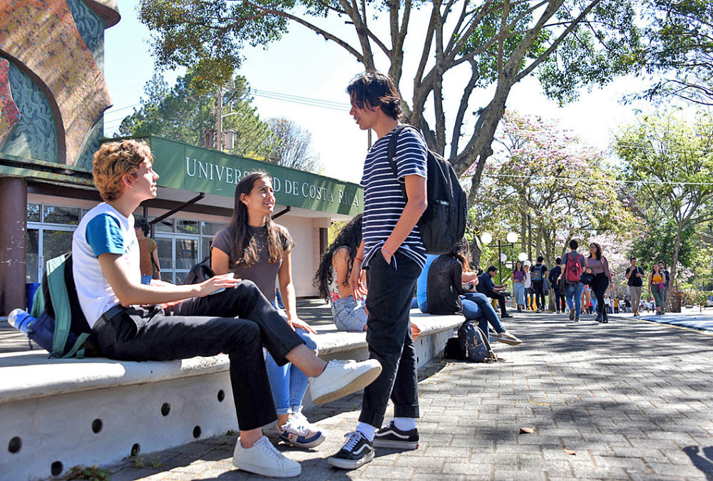 3 estudiantes conversando en el pretil de la UCR