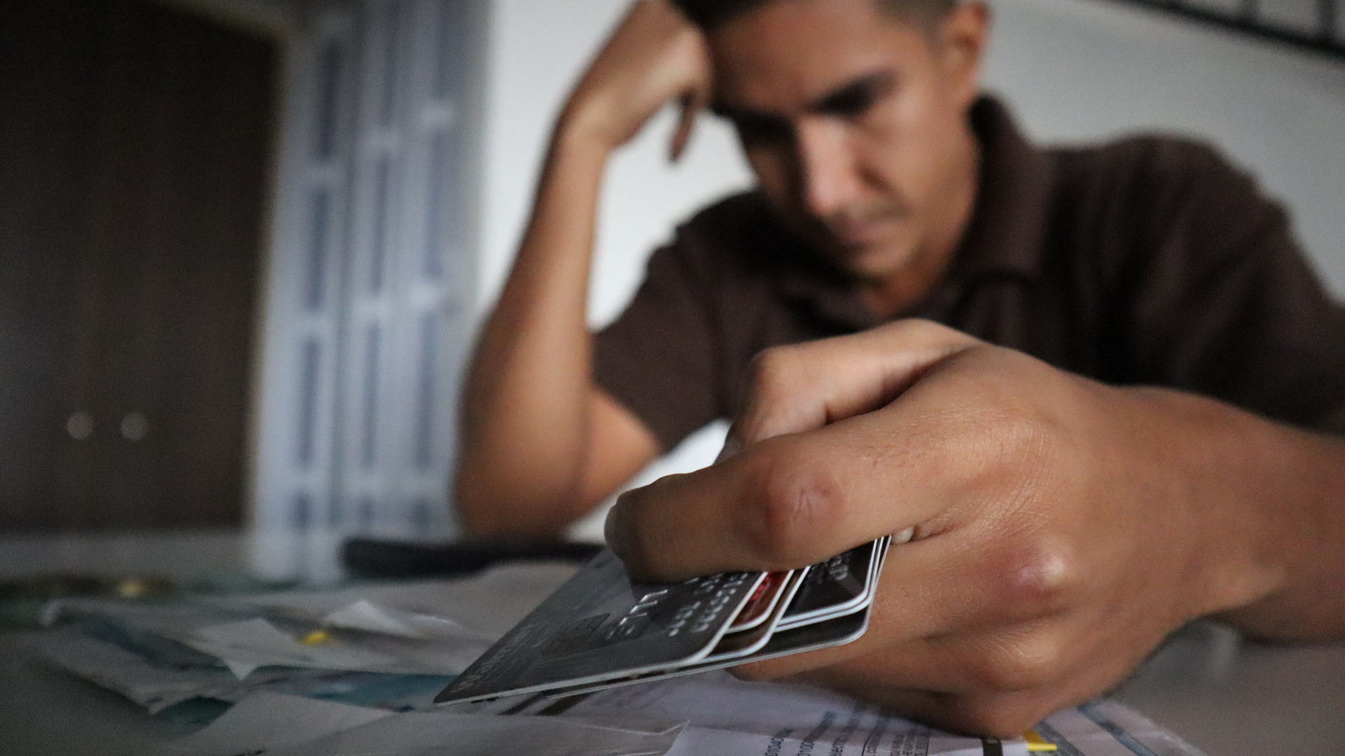 Hombre agobiado por las cuentas por pagar y con tarjetas de crédito en la mano