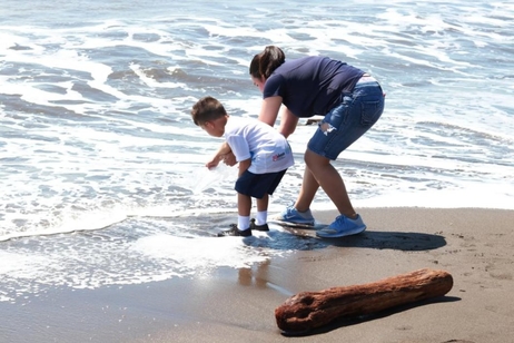 Un niño y una joven liberan un pez a la orilla del mar