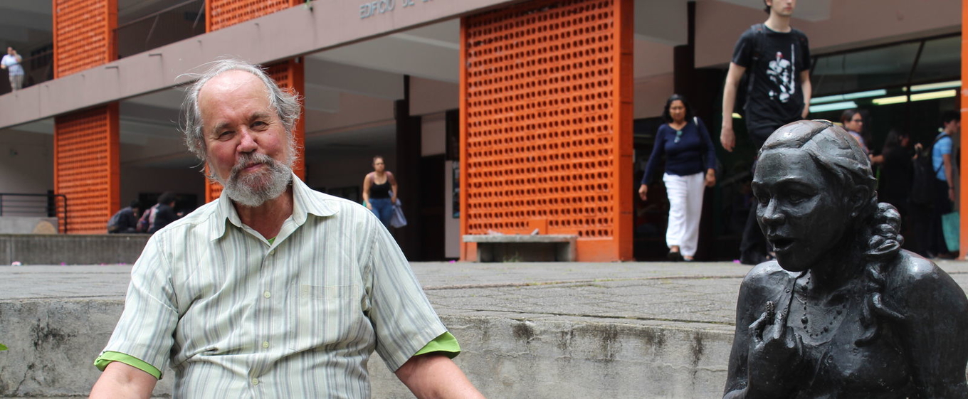 Antropólogo Carlos Rodrigues sentado junto a una estatua en el pretil