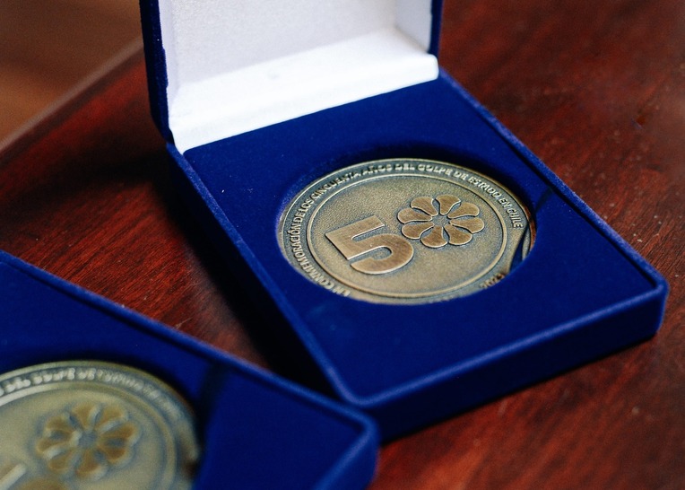 Moneda dorada en un estuche azul. La moneda tiene un gran número cincuenta donde el cero es …