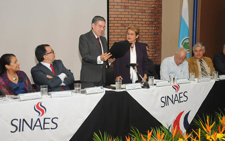 El Lic. Guillermo Vargas, presidente del Sinaes,  entregó el certificado a la Dra. Yamileth …