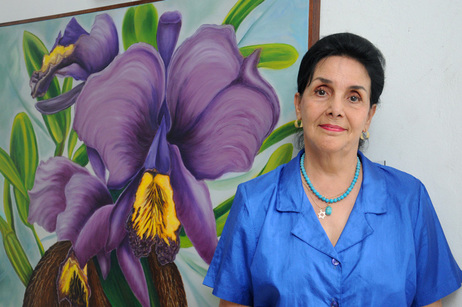 La artista Nancy Hidalgo junto a su pintura de la Guaria morada (foto Laura Rodríguez R.).