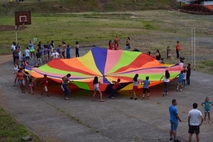 Grupo de personas jóvenes juegan alrededor de una gran manta de colores