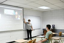La profesora María Luisa Ramírez utiliza parlantes, micrófono y proyecta en la pantalla el Zoom …