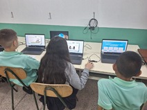 Dos niños y una niña de la Escuela Juan Santamaría de Cirrí de Naranjo sentados frente a …